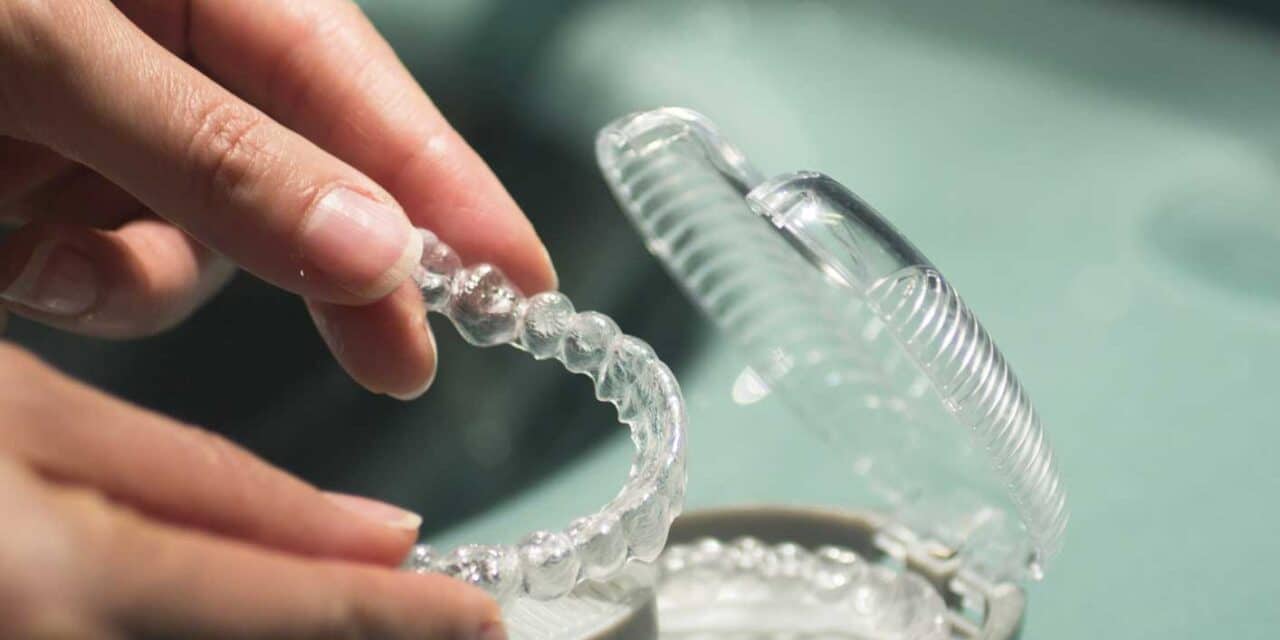 hands putting retainer in case at bathroom sink to illustrate orthodontic retention programs